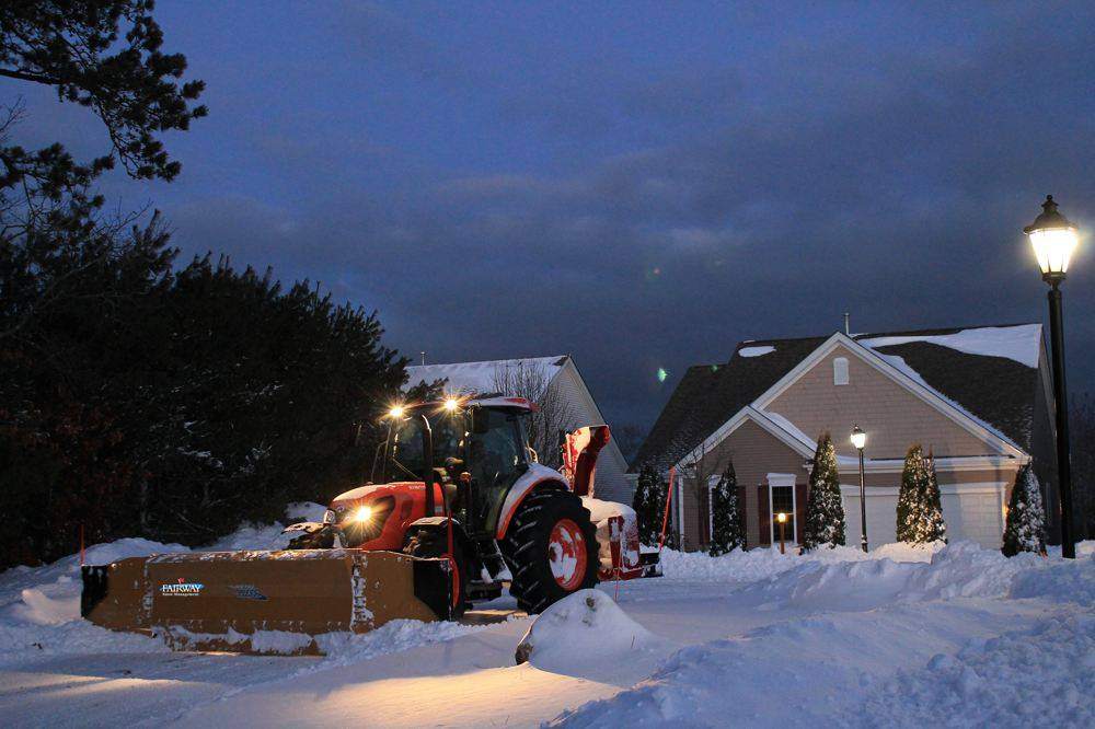 Fairway Snow Management tractor plowing Pinehills, Plymouth at dusk