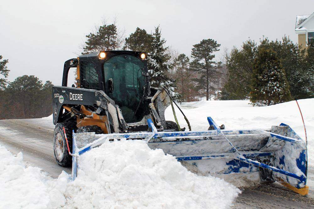 Fairway skid-steer with pusher box clearing a drive